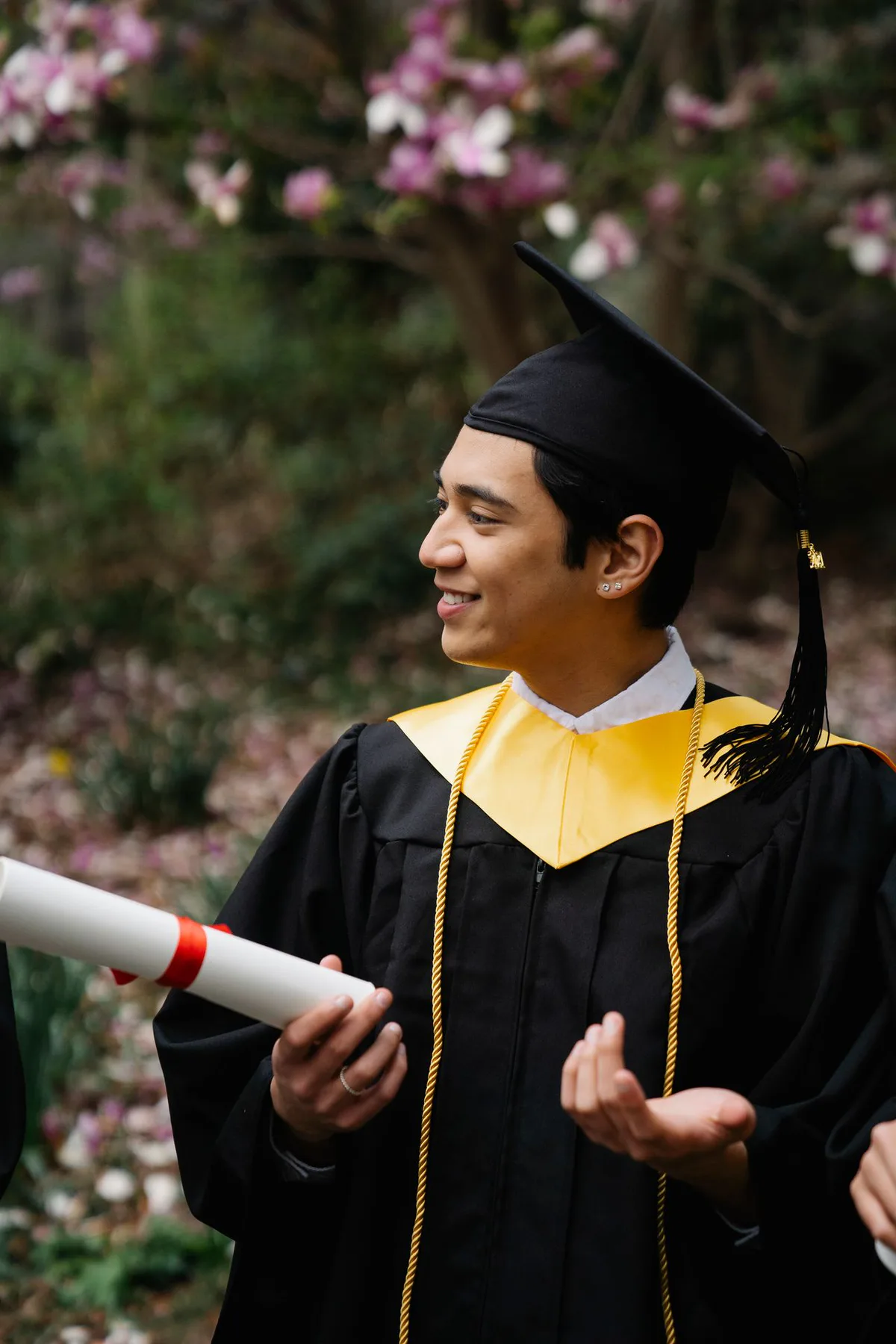 Persona graduada con birrete y diploma, entre las flores
